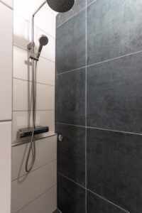 Walk-in shower with rain showerhead and dark tiles in Studio Belma Brela