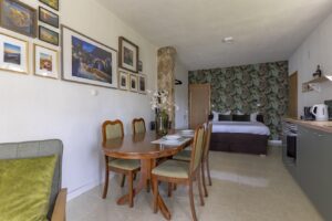 Dining area and bedroom Studio Brent Brela with wall art and green feature wall