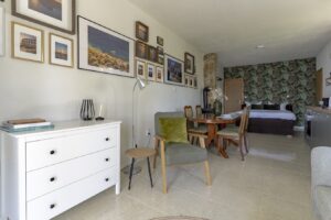 Cozy sitting area Studio Brent Brela with armchair, dresser and wall gallery