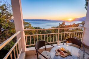 Balcony sunset view over the Adriatic Sea with table and wine glasses Studio Brent